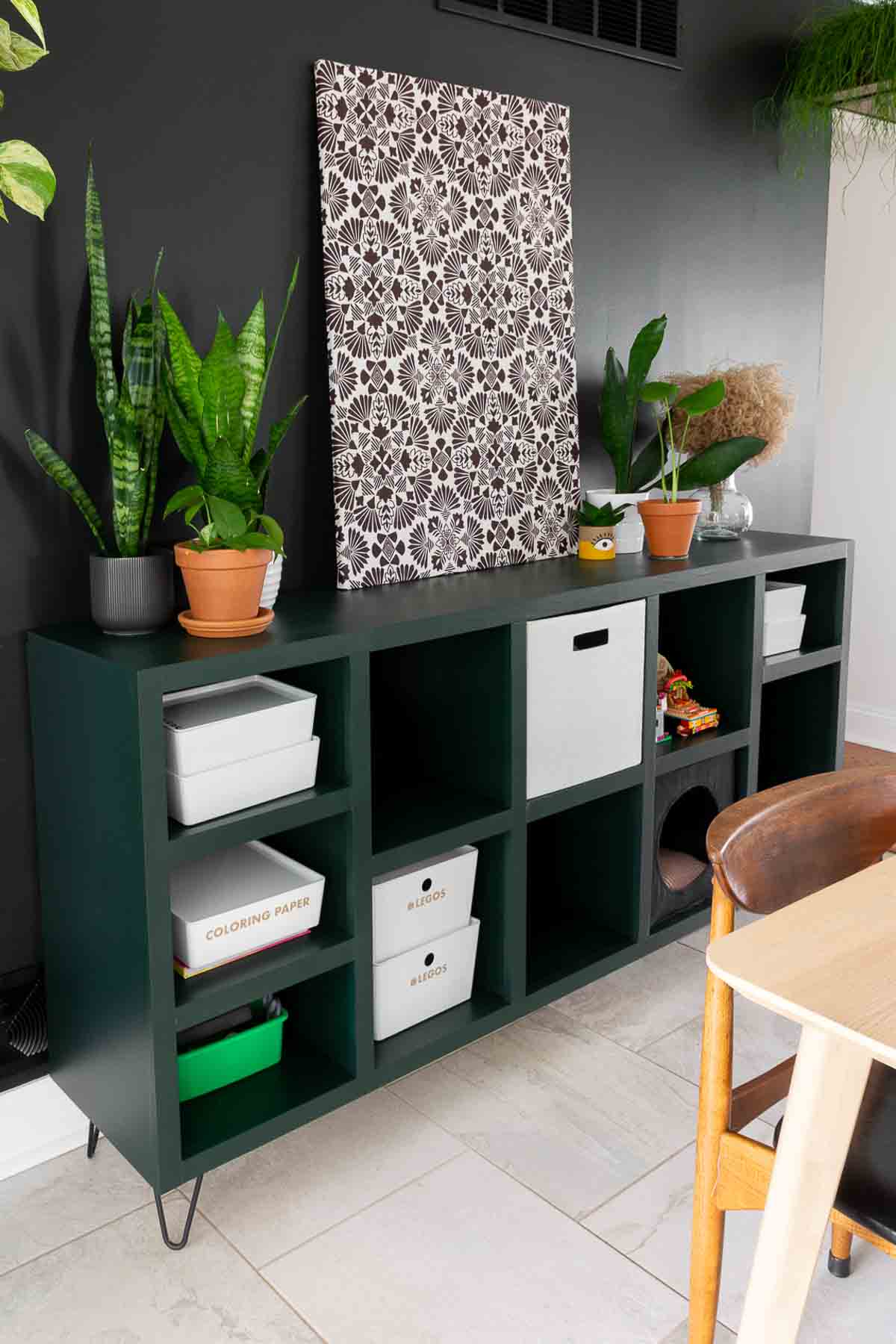 DIY cubby storage shelf painted dark green with white baskets and bins inside.
