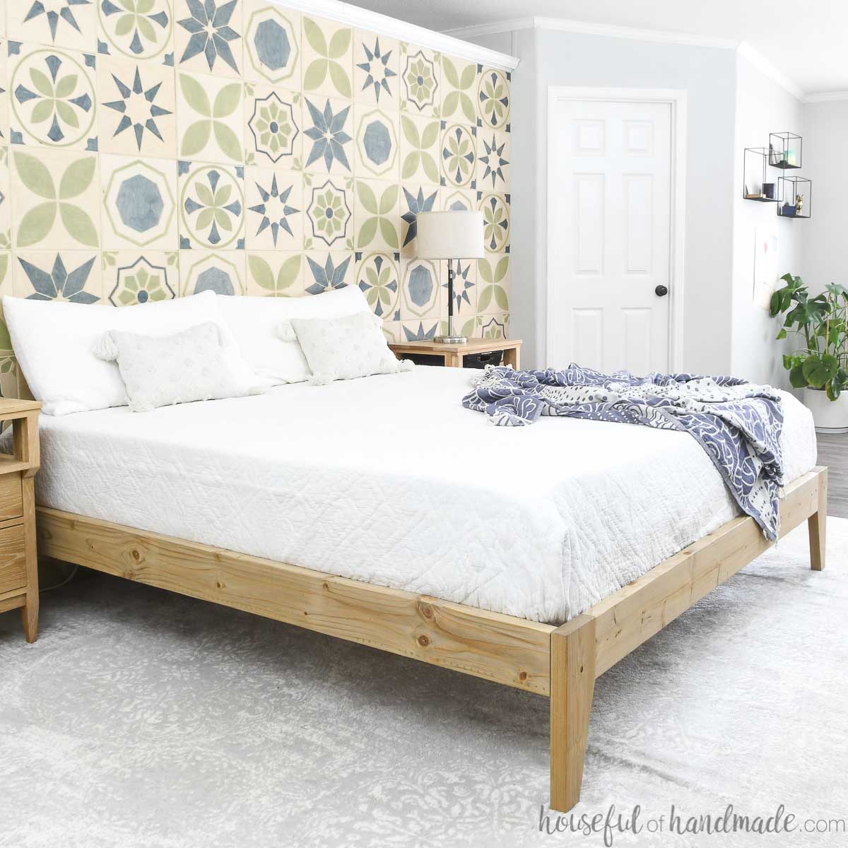 Modern platform bed with mattress and white blanket in a bedroom.