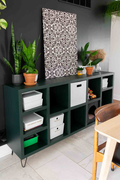 DIY cubby storage shelf painted dark green with white baskets and bins inside. 