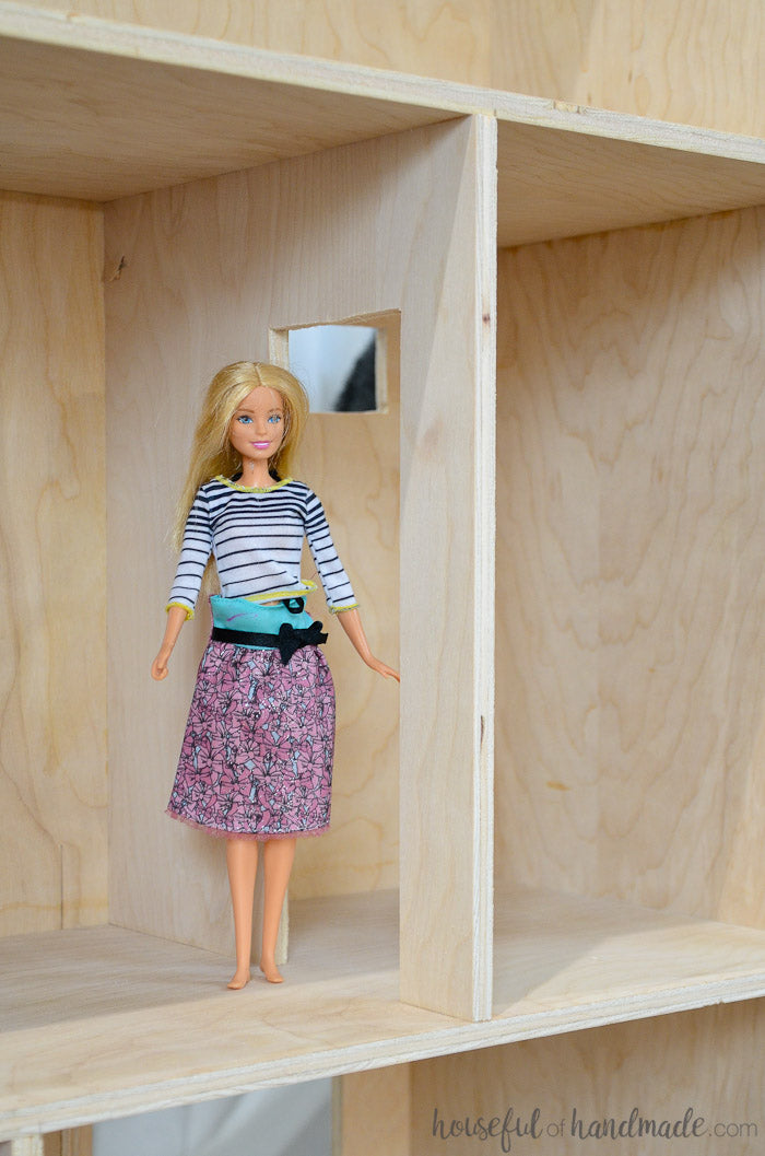 Barbie inside the dollhouse next to a door tall enough for it to go through. 