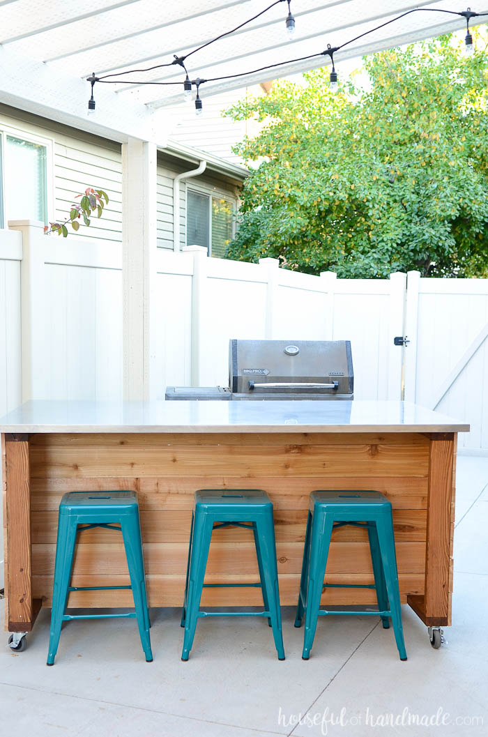 Cedar clad outdoor kitchen with barstools for seating.